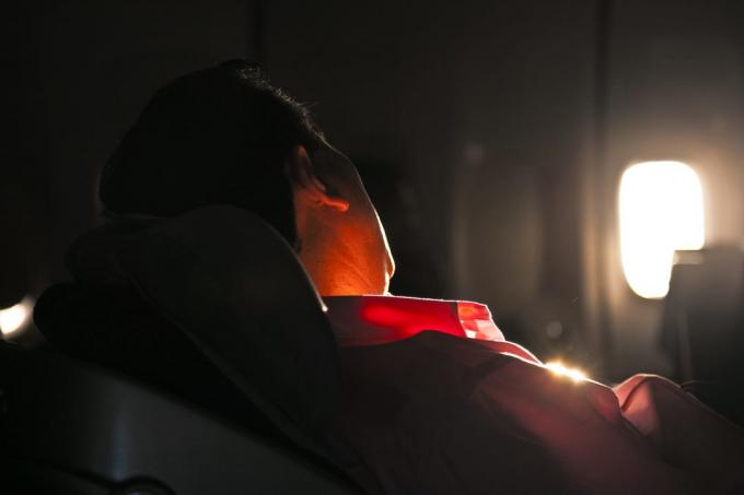 mand sovende i sædet af et fly i solopgang